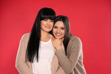 Portrait of young woman and her mature mother on color background