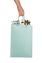 Woman holding paper shopping bag full of gift boxes on white background, closeup