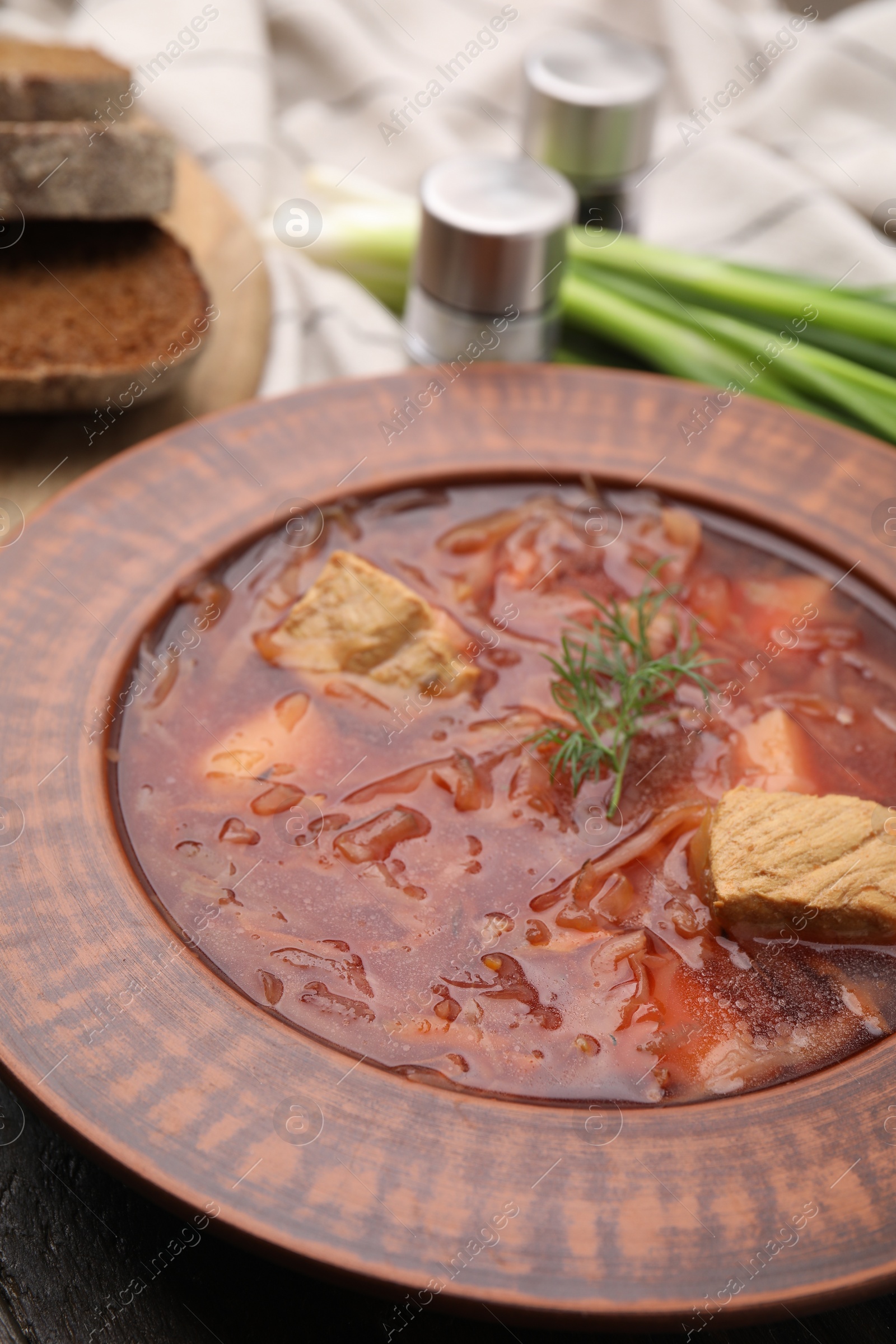 Photo of Bowl of delicious borscht on table, closeup.