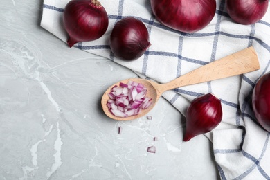 Flat lay composition with cut and whole red onions on grey marble table. Space for text