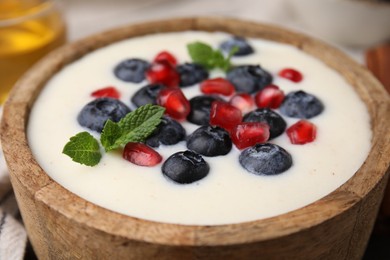 Photo of Bowl of delicious semolina pudding with blueberries, pomegranate and mint, closeup