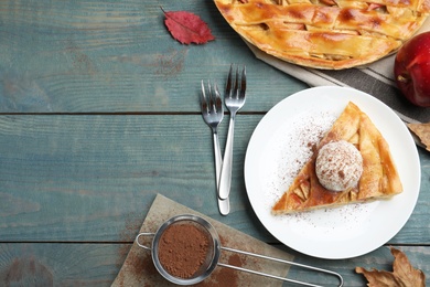 Slice of traditional apple pie with ice cream served on blue wooden table, flat lay. Space for text