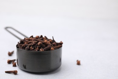 Photo of Aromatic cloves in scoop on light table, closeup. Space for text