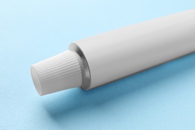 Photo of Tube of ointment on light blue background, space for text