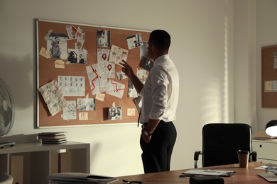 Detective looking at evidence board in office