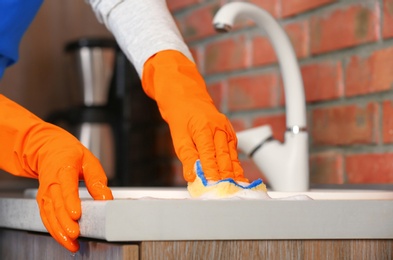 Photo of Woman cleaning counter with sponge in kitchen, closeup