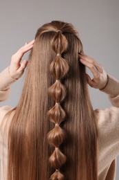 Woman with braided hair on grey background, back view