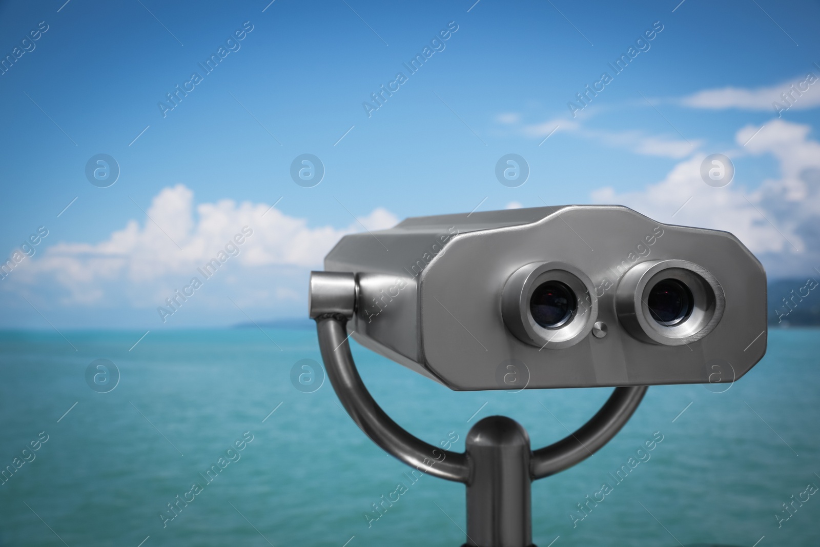 Photo of Metal tower viewer installed near sea, space for text. Mounted binoculars