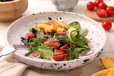 Photo of Delicious salad with vegetables and peach in bowl on table, closeup