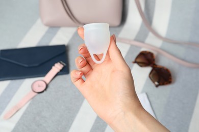 Woman holding menstrual cup on blurred background, above view