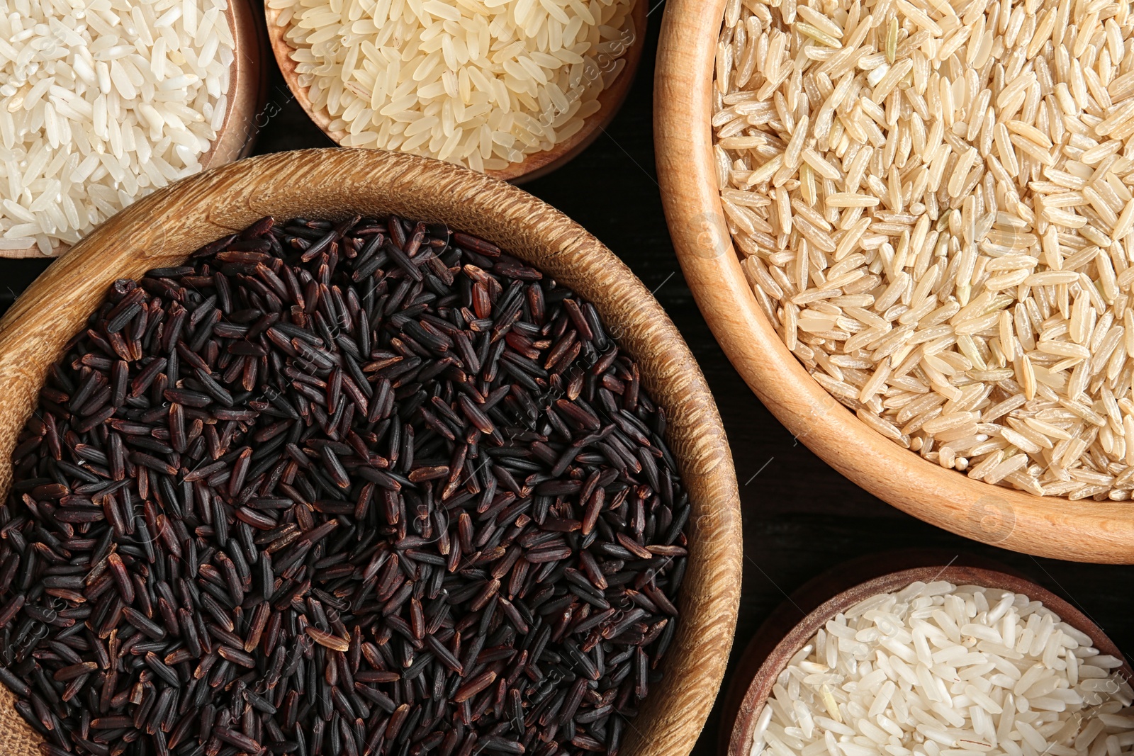 Photo of Flat lay composition with brown and other types of rice in bowls