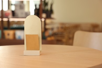 Photo of Menu holder on wooden table in cafe, space for text