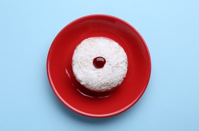 Photo of Hanukkah donut with jelly and powdered sugar on light blue background, top view