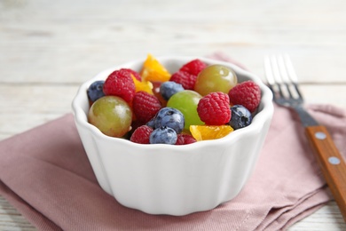 Photo of Fresh tasty fruit salad on white wooden table, closeup