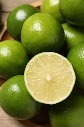 Photo of Whole and cut fresh limes on table, closeup