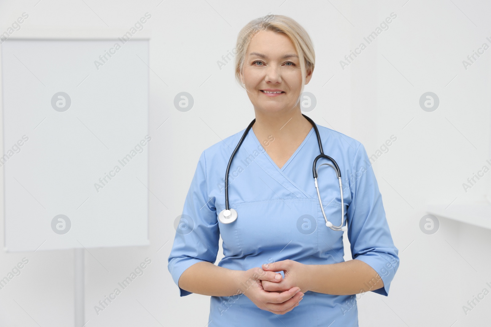 Photo of Professional doctor wearing uniform near flipchart in clinic