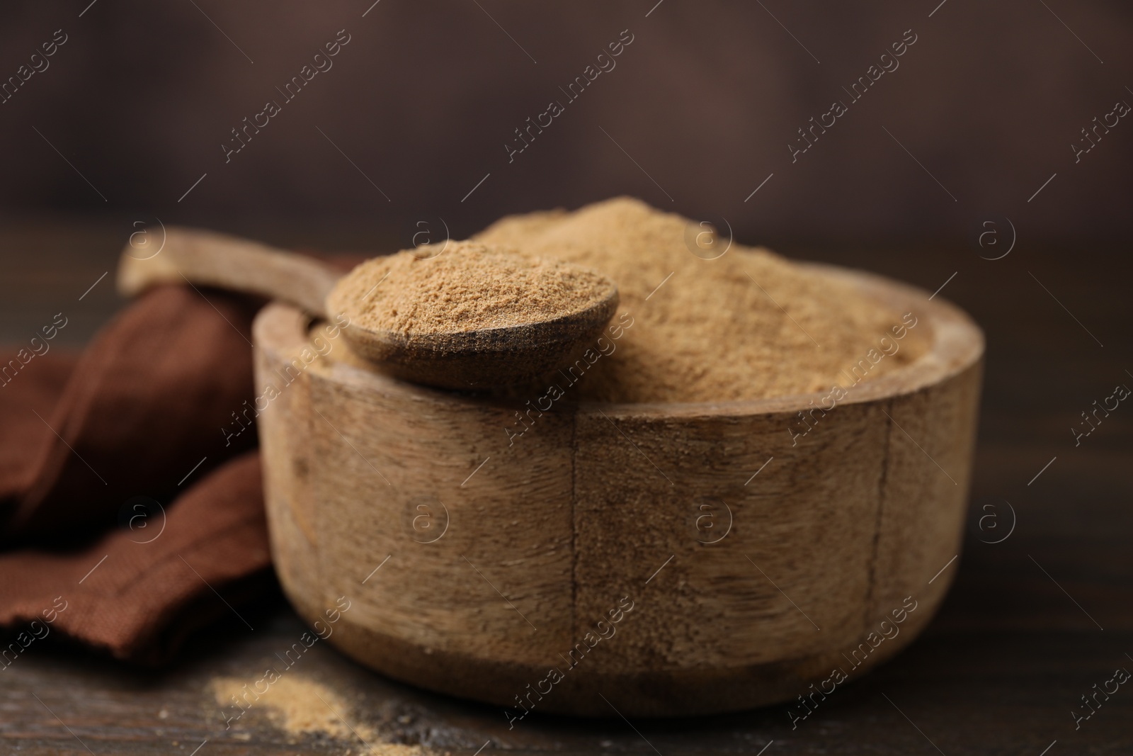 Photo of Dietary fiber. Psyllium husk powder in bowl and spoon on wooden table, closeup