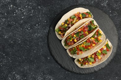 Photo of Tasty tacos with vegetables on black textured table, top view. Space for text