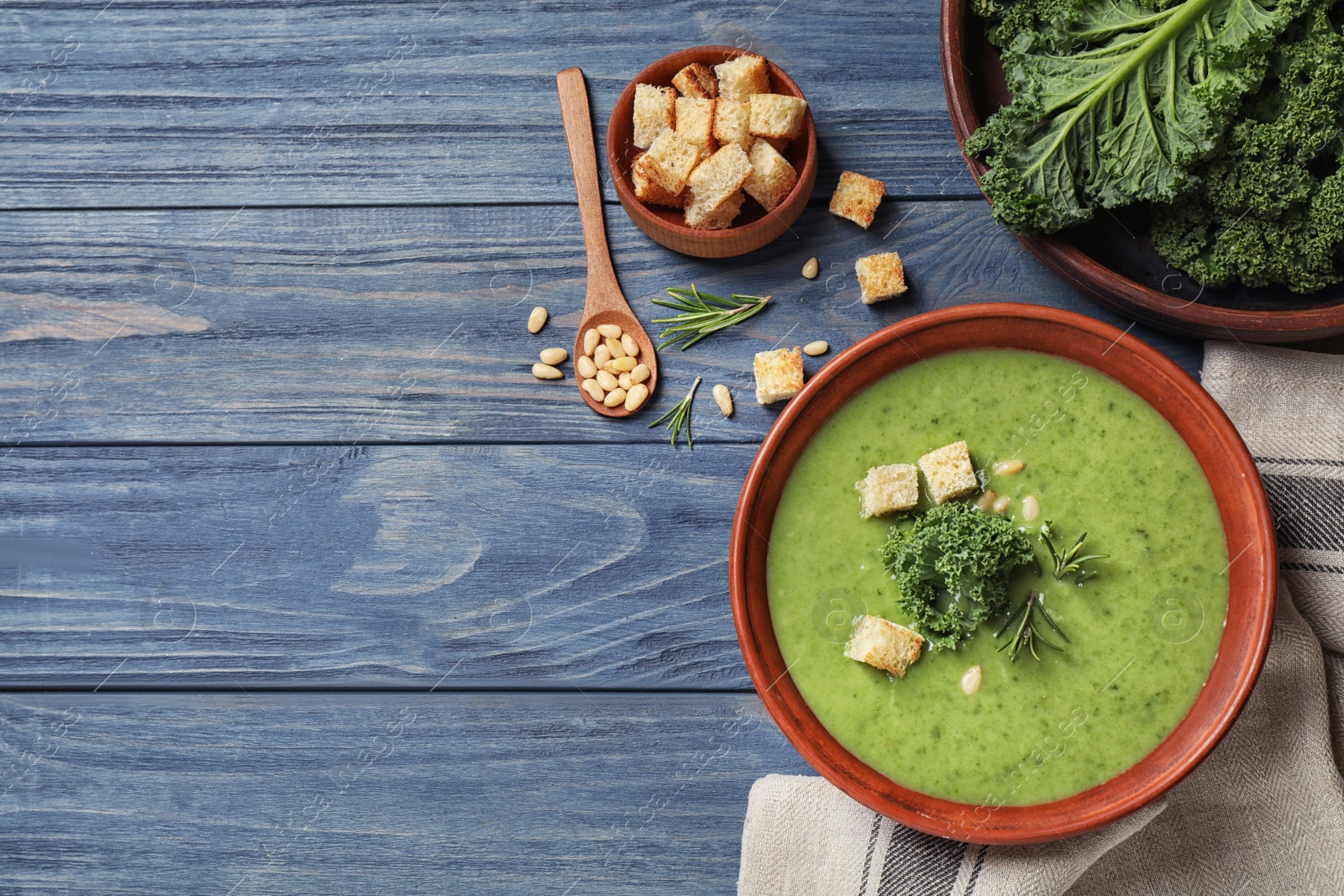 Photo of Tasty kale soup on blue wooden table, flat lay. Space for text