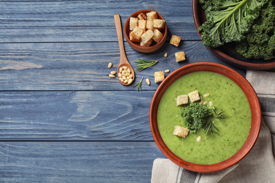 Photo of Tasty kale soup on blue wooden table, flat lay. Space for text