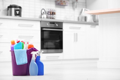 Photo of Bucket with cleaning supplies on floor in kitchen. Space for text