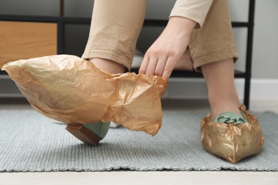 Woman wearing shoe covers onto her mules indoors, closeup