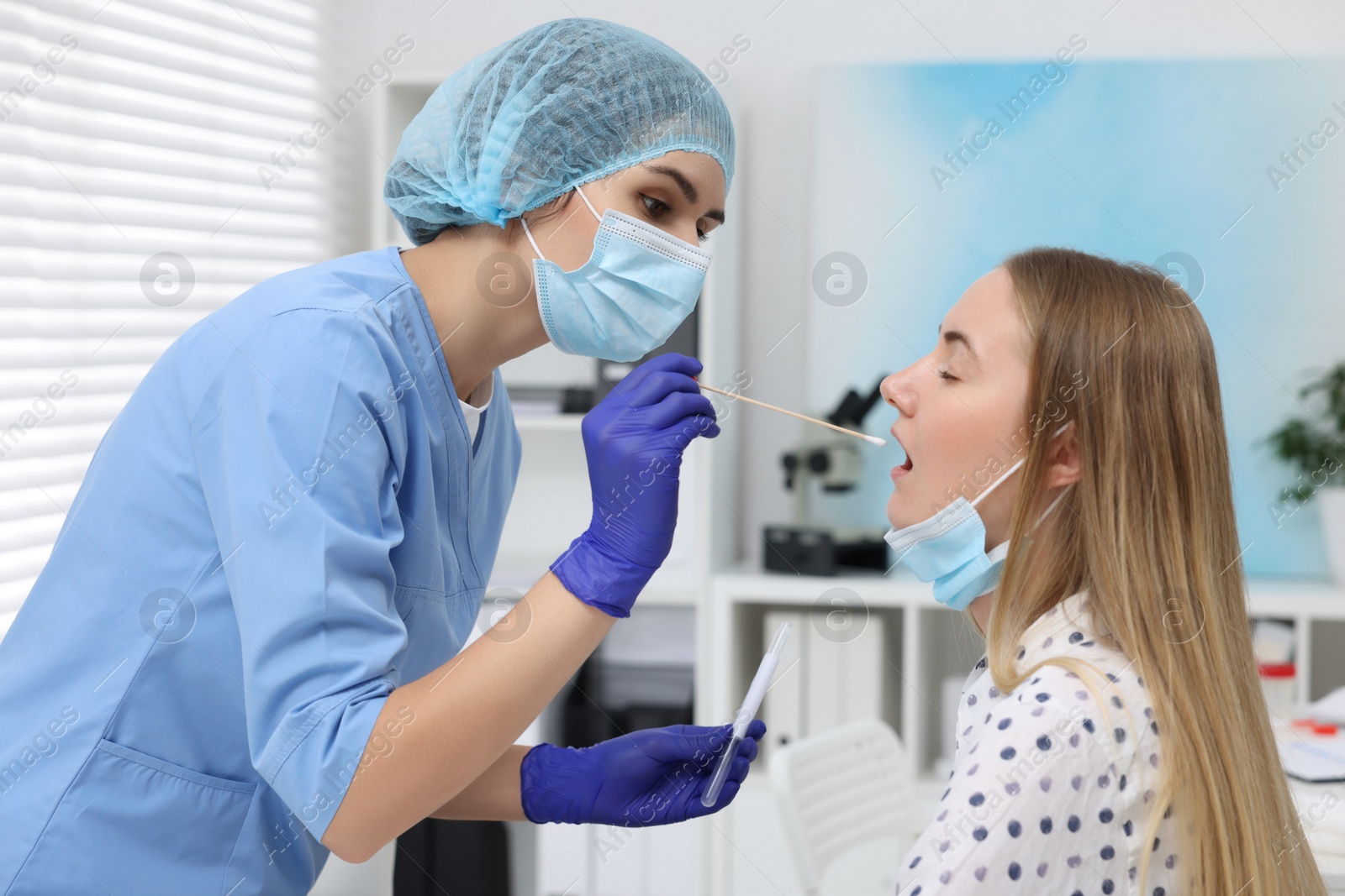 Photo of Laboratory testing. Doctor taking sample from patient's mouth with cotton swab in hospital