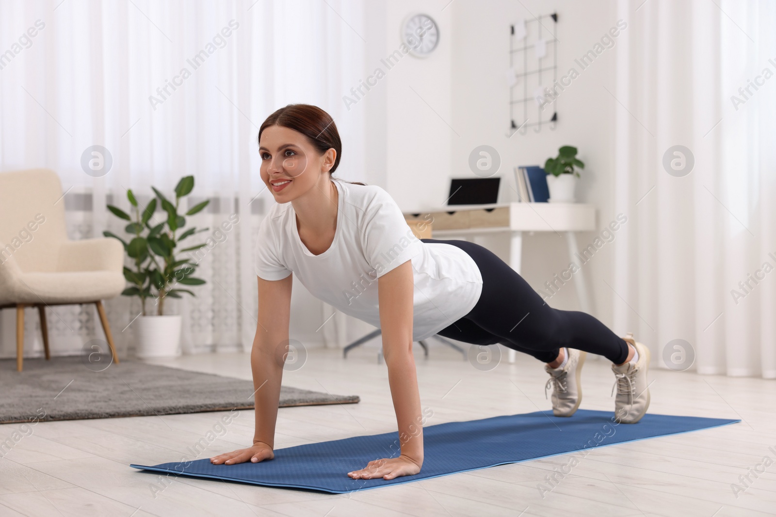 Photo of Happy woman doing plank exercise at home. Morning routine