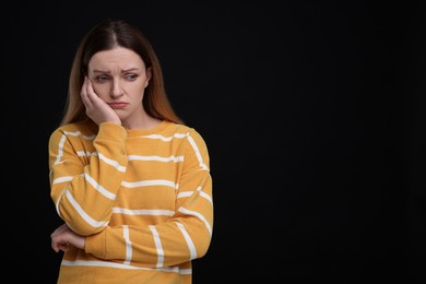 Portrait of sad woman on black background, space for text