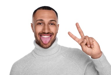 Photo of Happy young man showing his tongue and V-sign on white background