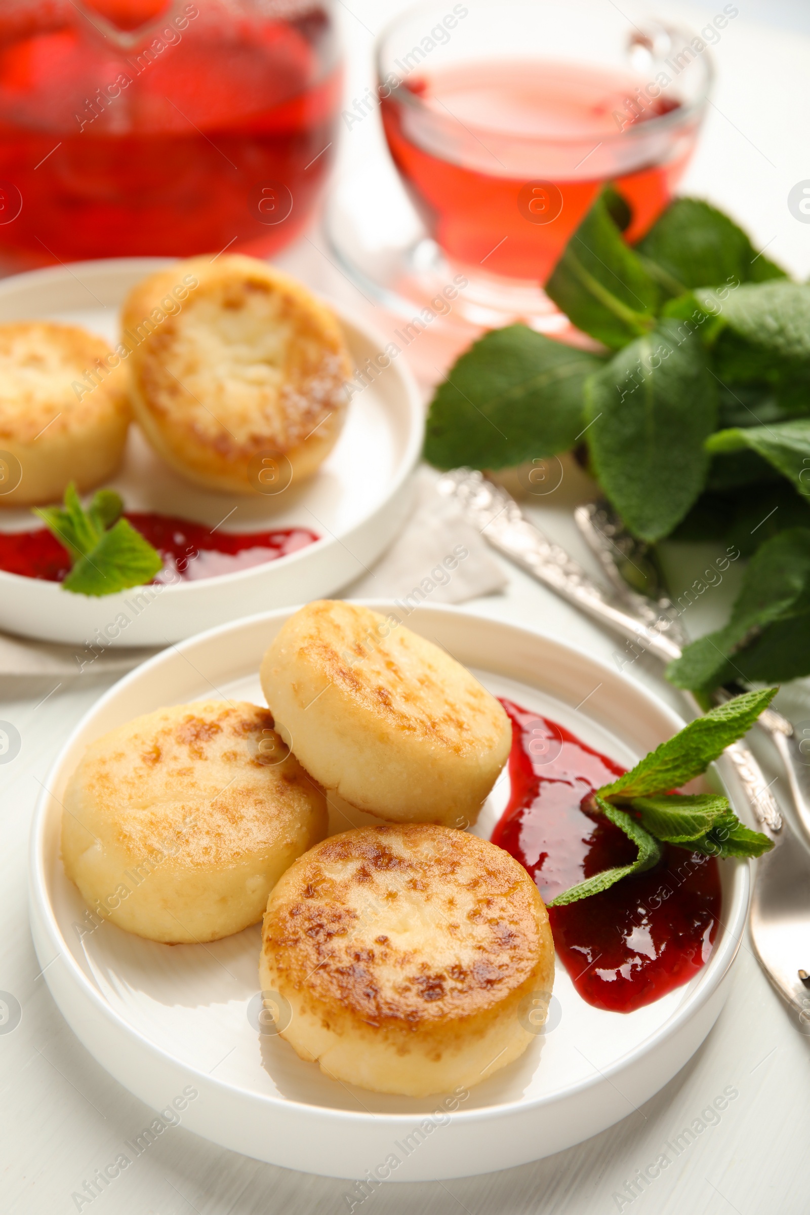 Photo of Delicious cottage cheese pancakes with jam and mint on white wooden table