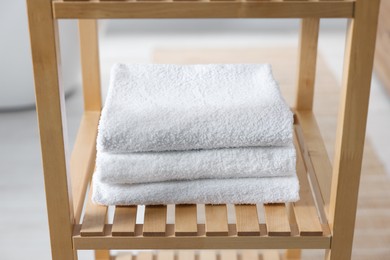 Photo of Stacked bath towel on wooden shelf indoors