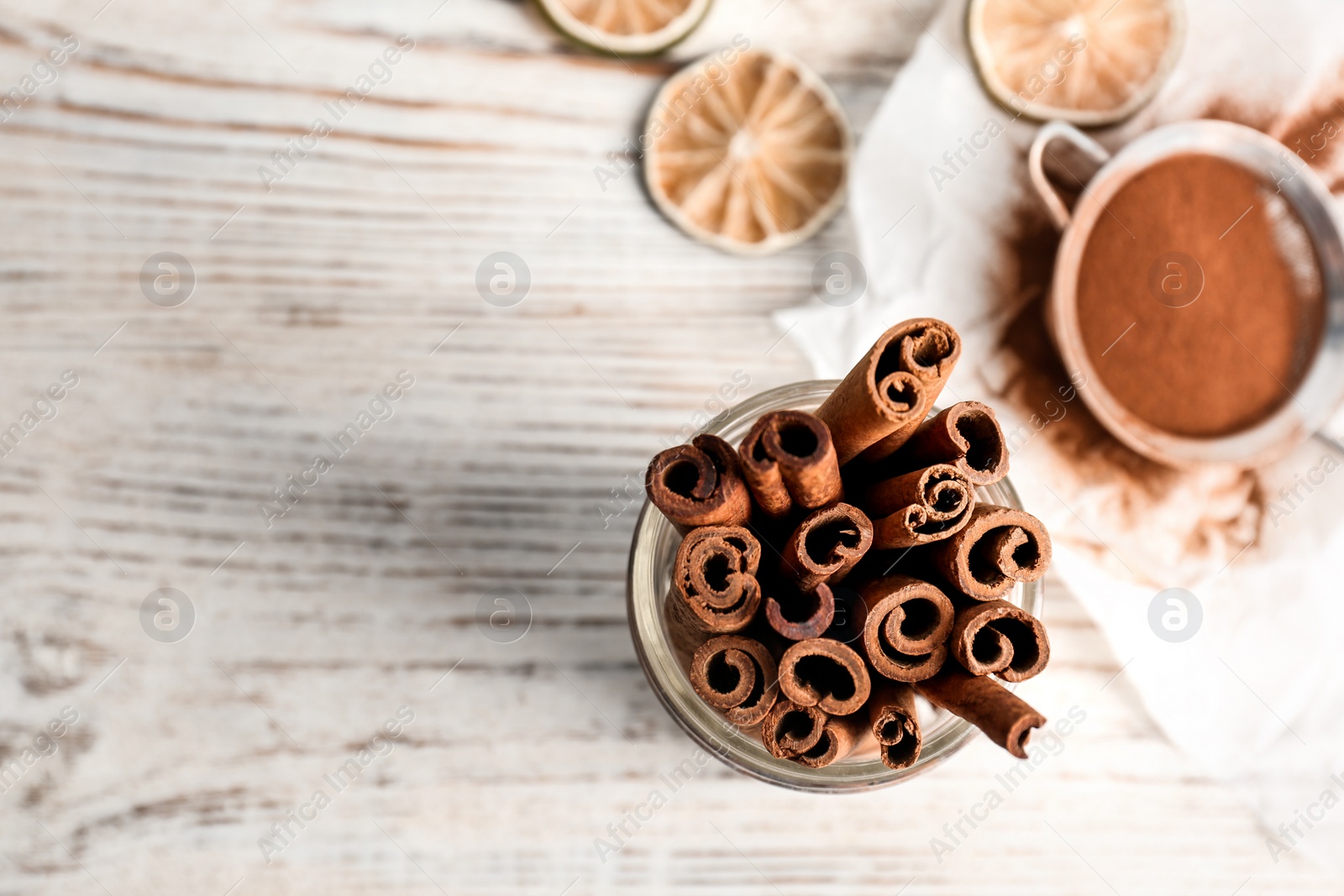 Photo of Jar with aromatic cinnamon sticks on wooden background