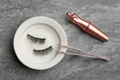 Flat lay composition with magnetic eyelashes and accessories on grey table