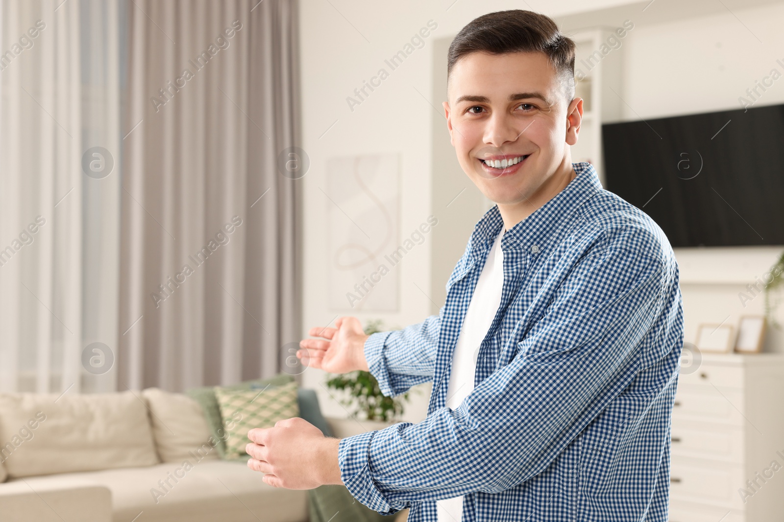 Photo of Handsome man inviting to come in room at home