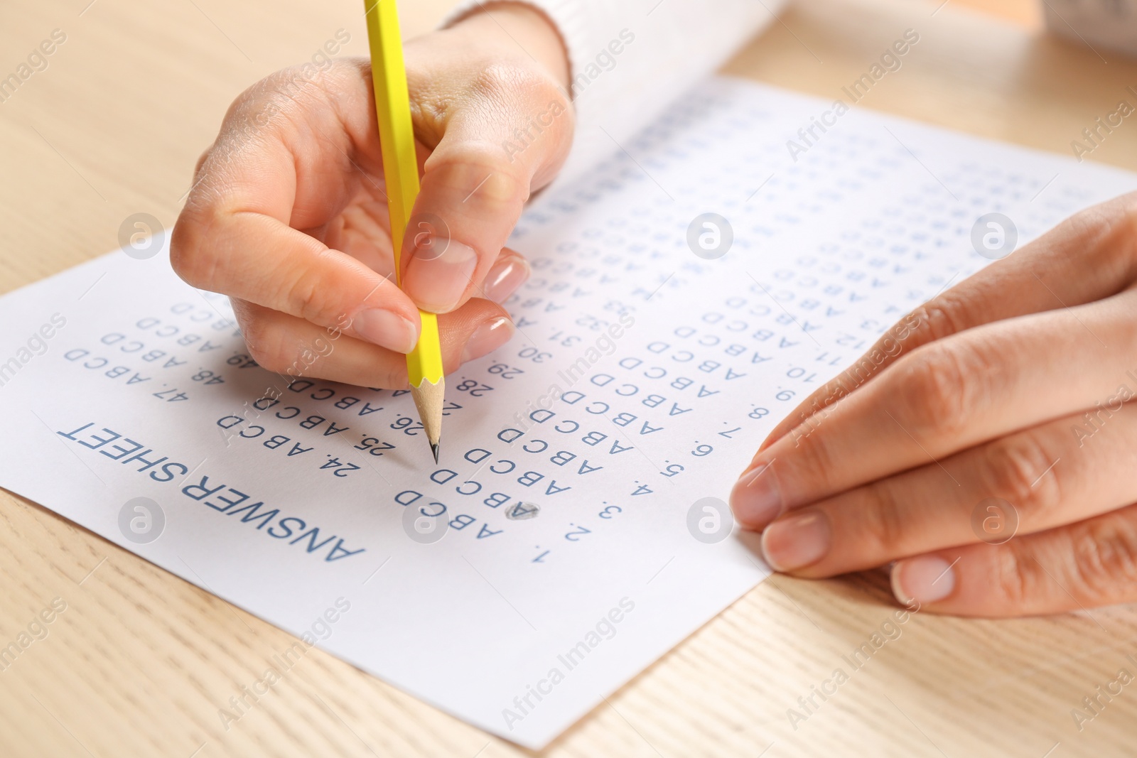 Photo of Student filling answer sheet at table, closeup