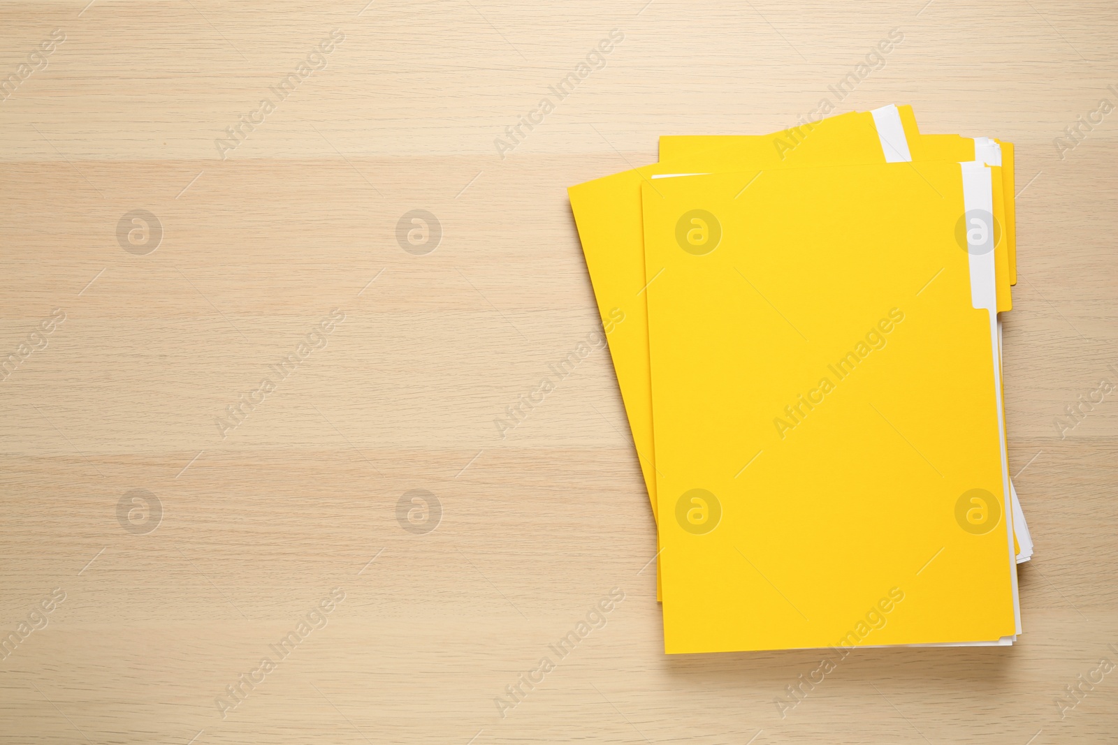 Photo of Yellow files with documents on wooden table, top view. Space for text