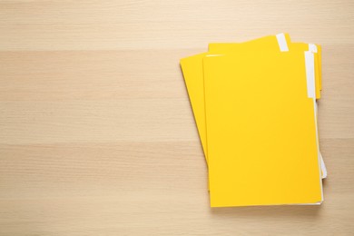 Photo of Yellow files with documents on wooden table, top view. Space for text