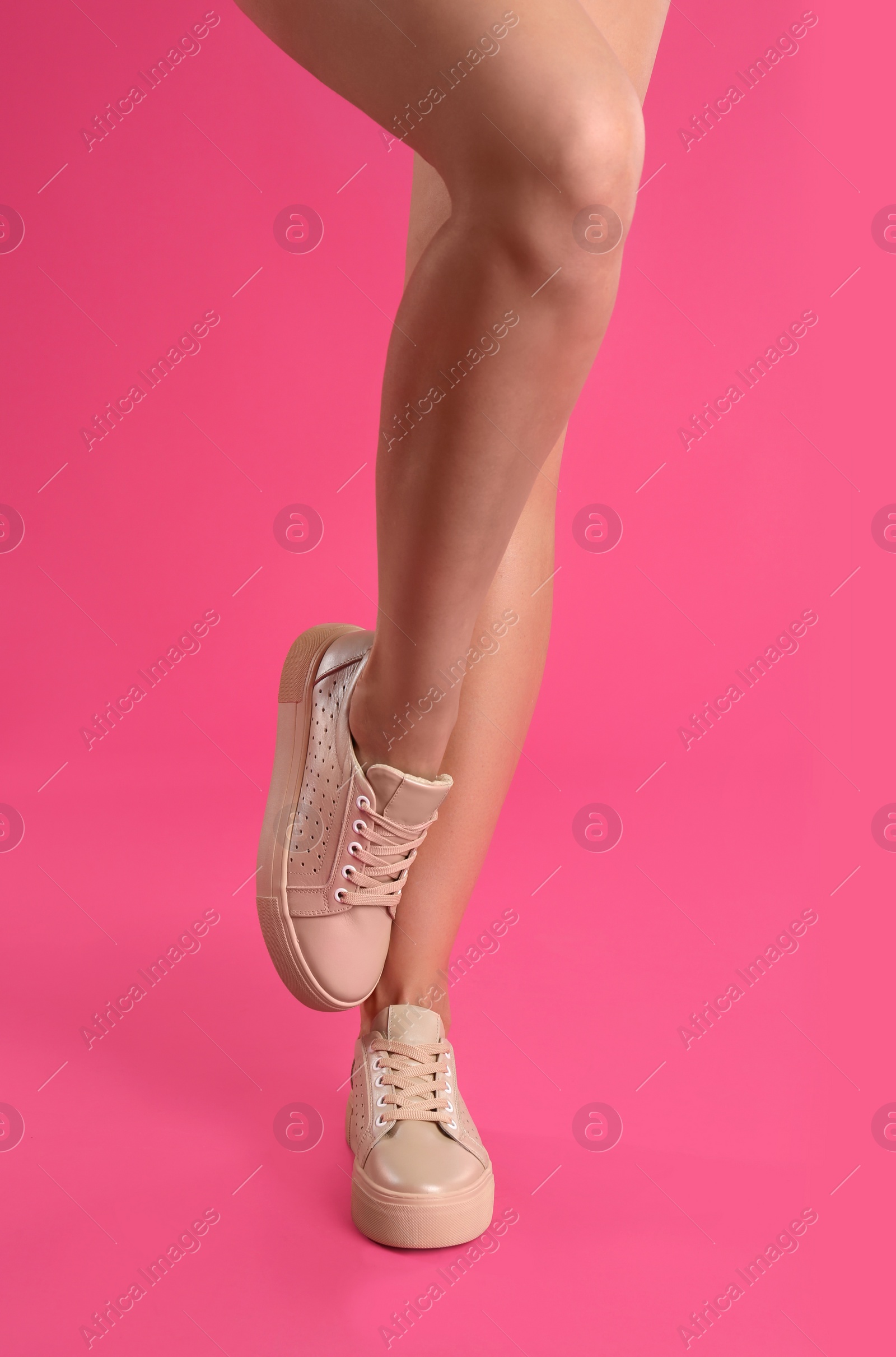 Photo of Woman wearing shoes on pink background, closeup