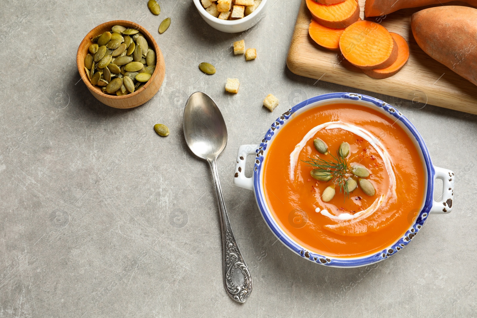 Photo of Flat lay composition with bowl of sweet potato soup on table. Space for text