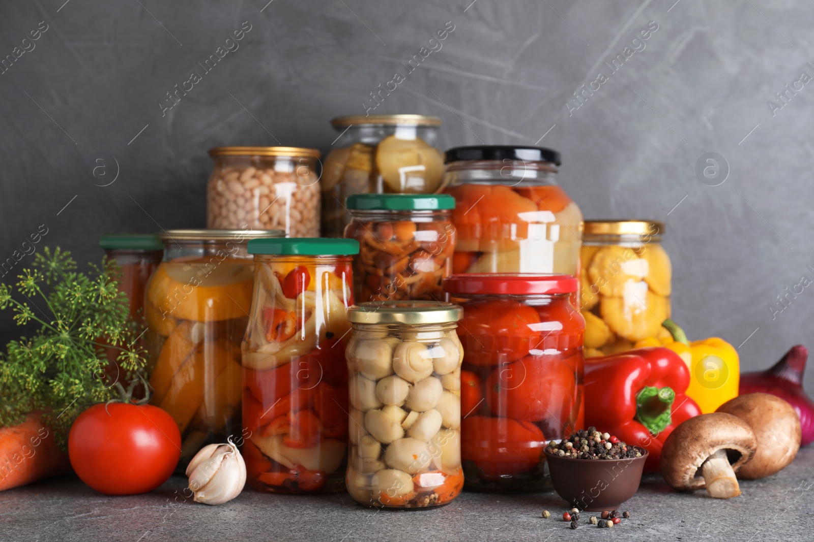 Photo of Jars of tasty pickled vegetables on grey table