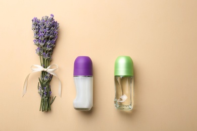 Photo of Female deodorants and lavender flowers on beige background, flat lay