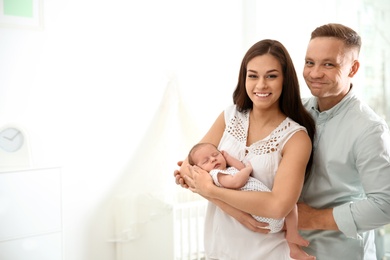 Photo of Happy couple with their newborn baby at home. Space for text