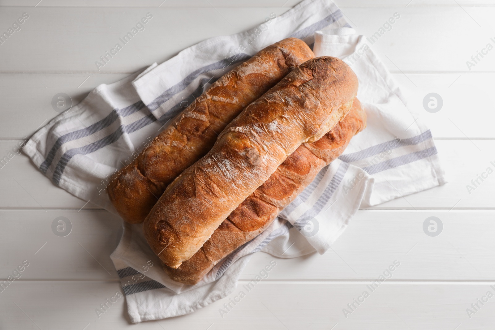 Photo of Fresh crispy ciabattas on white wooden table, top view