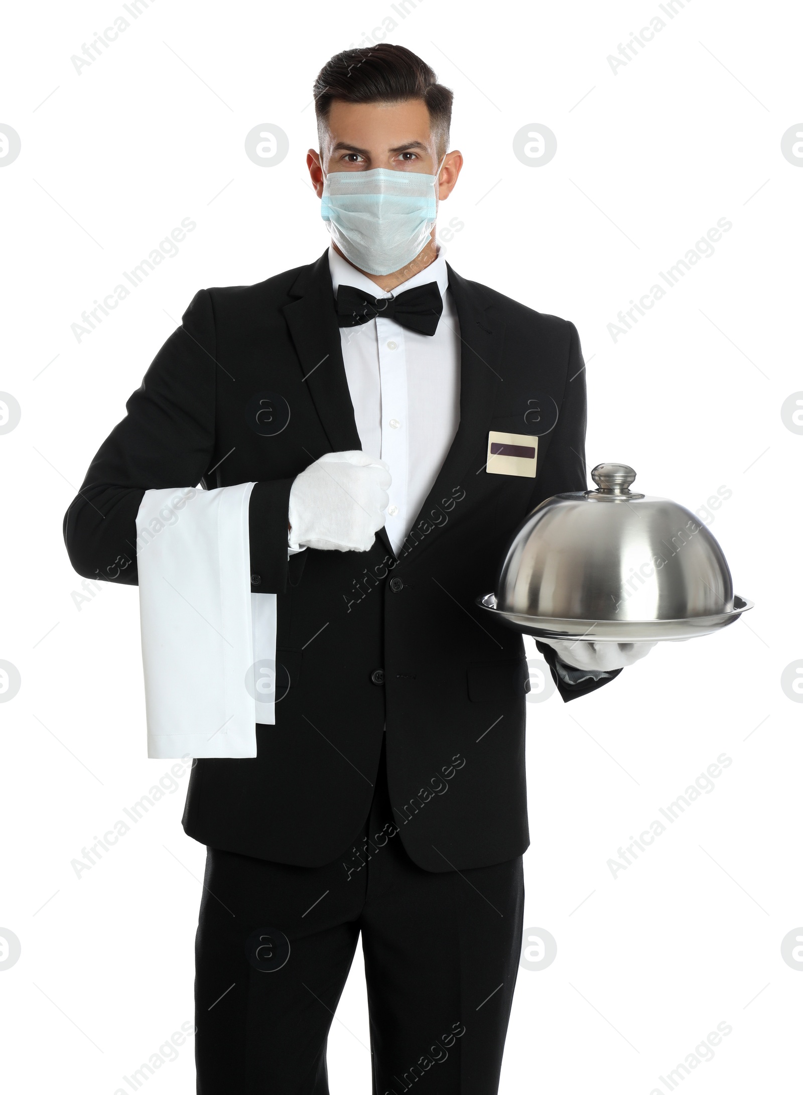 Photo of Waiter in medical face mask holding tray with lid on white background