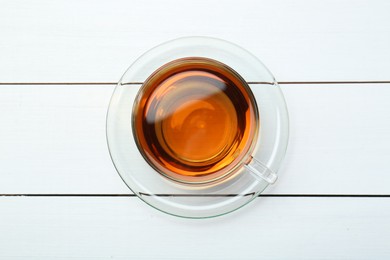 Photo of Glass cup of tea on white wooden table, top view