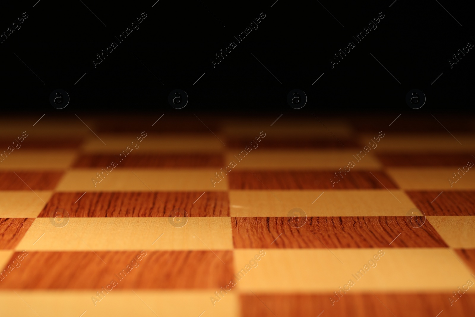 Photo of Checkered chessboard on dark background, closeup view