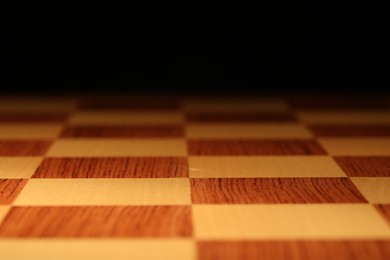 Checkered chessboard on dark background, closeup view