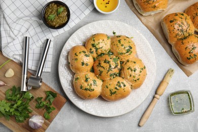 Traditional pampushka buns with garlic and herbs on grey table, flat lay