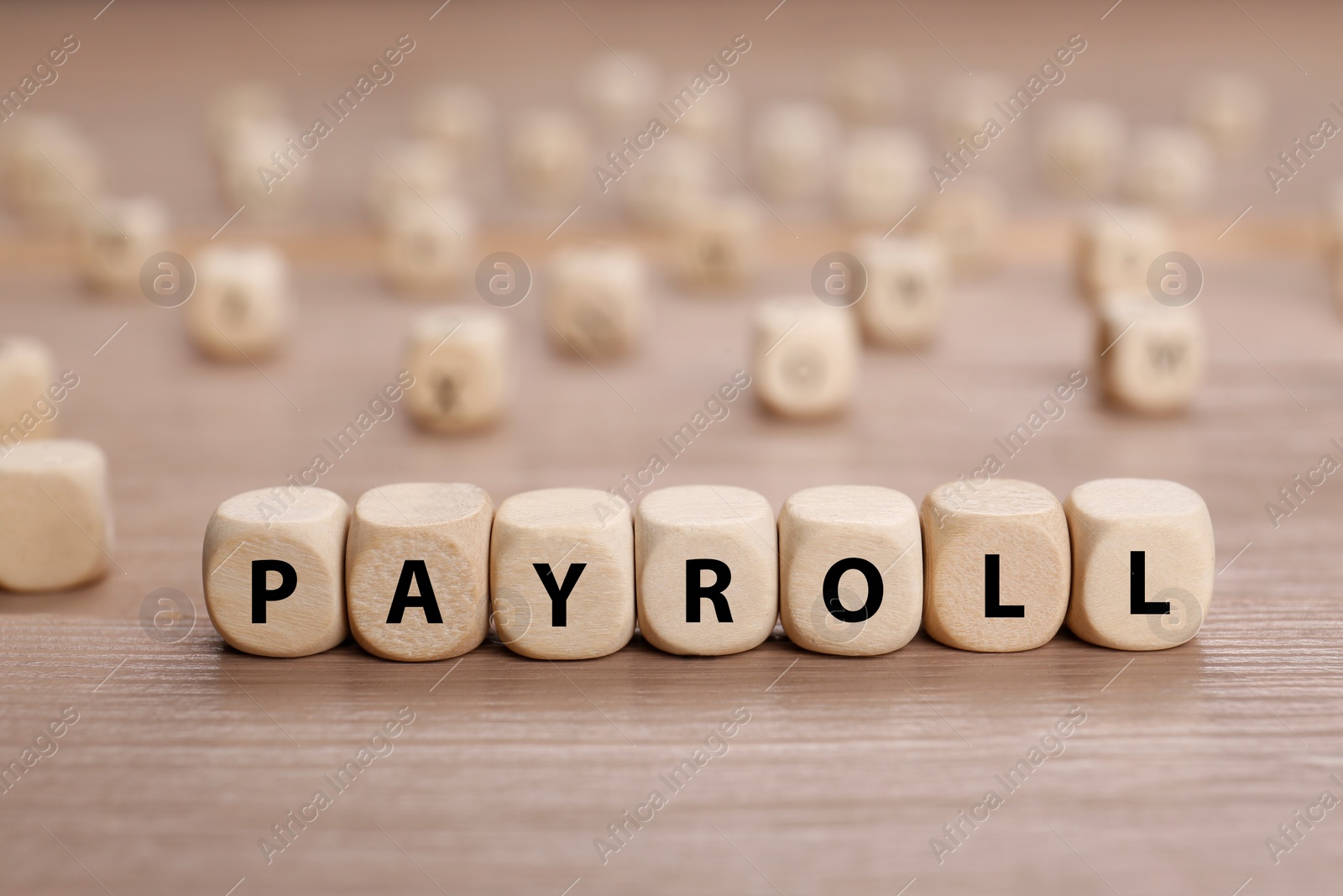 Photo of Word Payroll made of cubes on wooden table